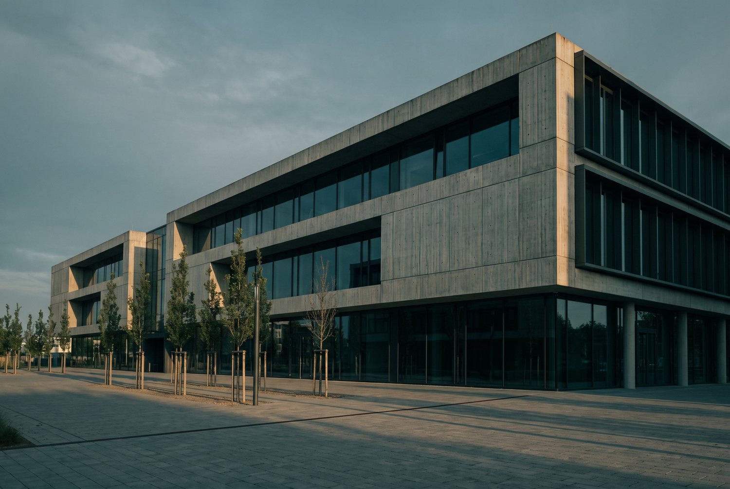 Moderne Gewerbeimmobilie aus Sichtbeton und Glas im Abendlicht
