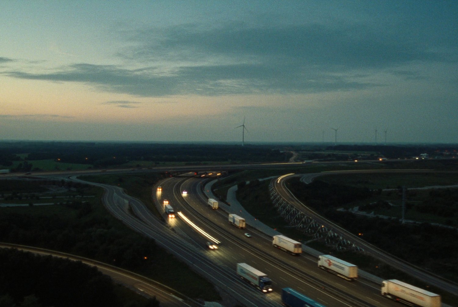 Luftaufnahme eines europäischen Autobahnkreuzes bei Dämmerung mit Güterverkehr
