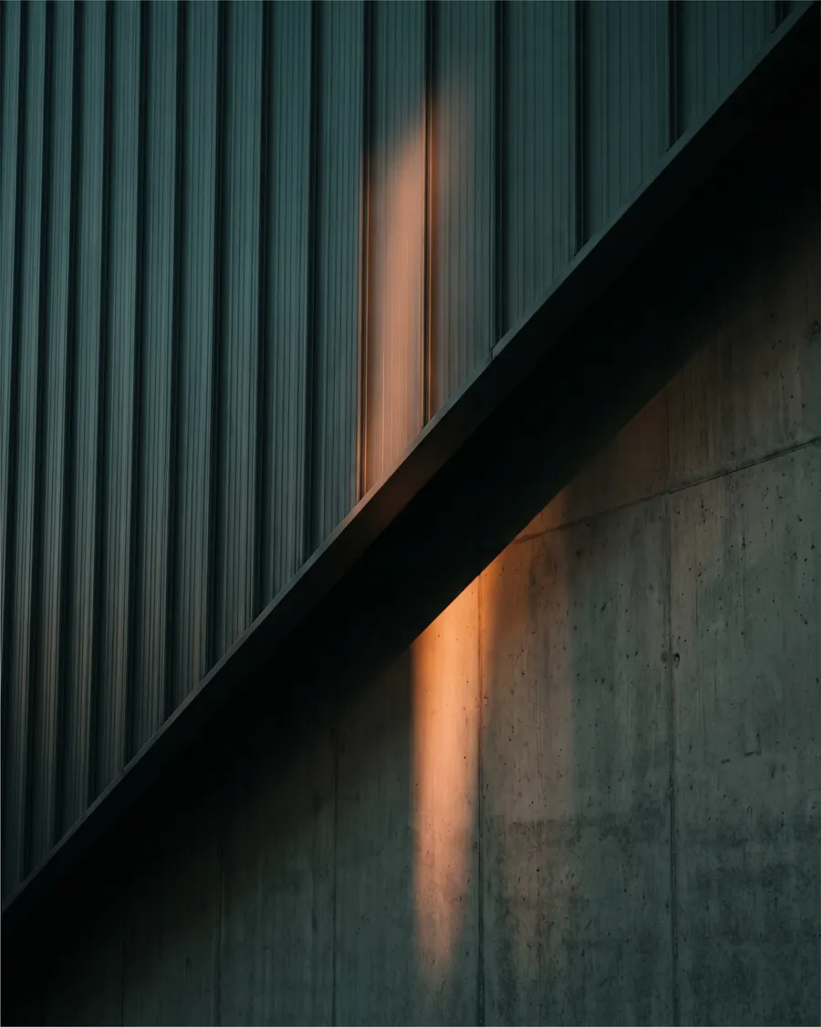 Detail einer dunklen Metall- und Betonfassade im Abendlicht