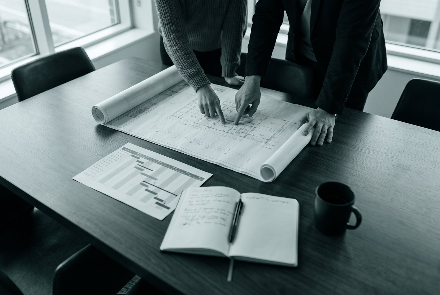 Projektplanung am Schreibtisch mit technischen Zeichnungen und Terminplan